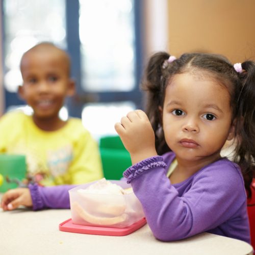 Pre-school children on their lunch break eating sandwiches.